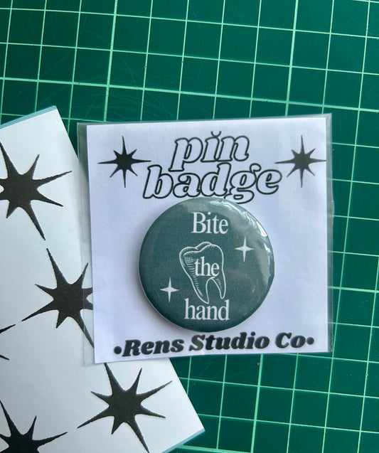 bite the hand pin badge